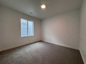 Neutral paint tones throughout with patterned carpeting, a white trim baseboard, a ceiling-mounted light fixture, and a window with white casing