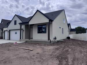 Modern-style stucco exterior with dark trim accents, a covered entry, and an attached two-car garage