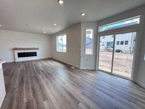 Spacious interior featuring wood-finish flooring, recessed lighting, and a contemporary linear electric fireplace with a wood mantle