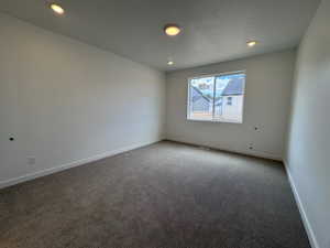 Spacious room featuring neutral carpeting, white baseboards, and recessed lighting