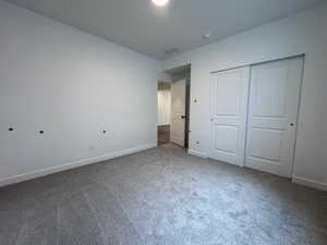 Neutral tone walls with white trim, gray carpet flooring, and a two-panel sliding closet door