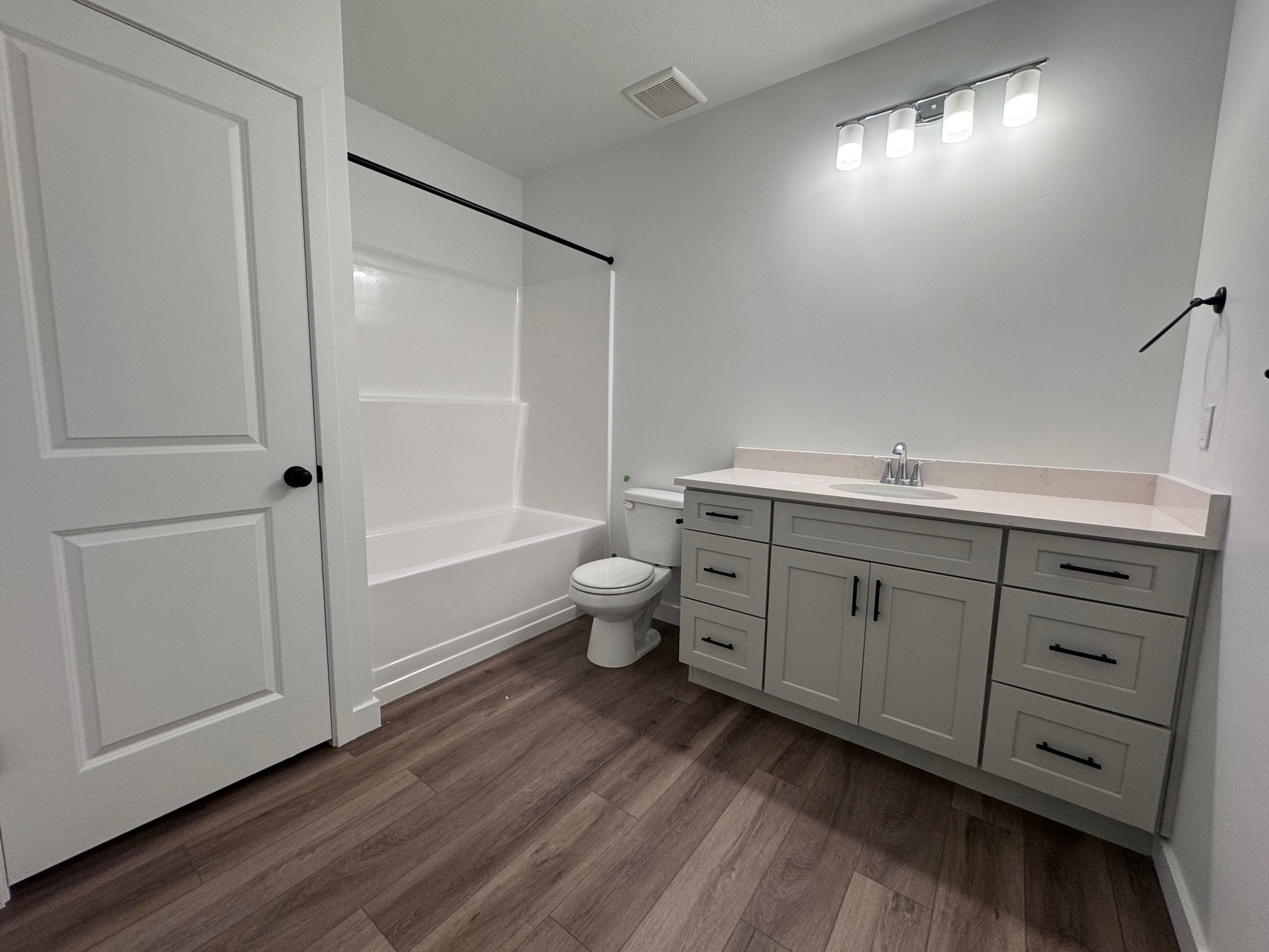 Bathroom featuring a single vanity with light-colored countertop, undermount sink, and matte black hardware