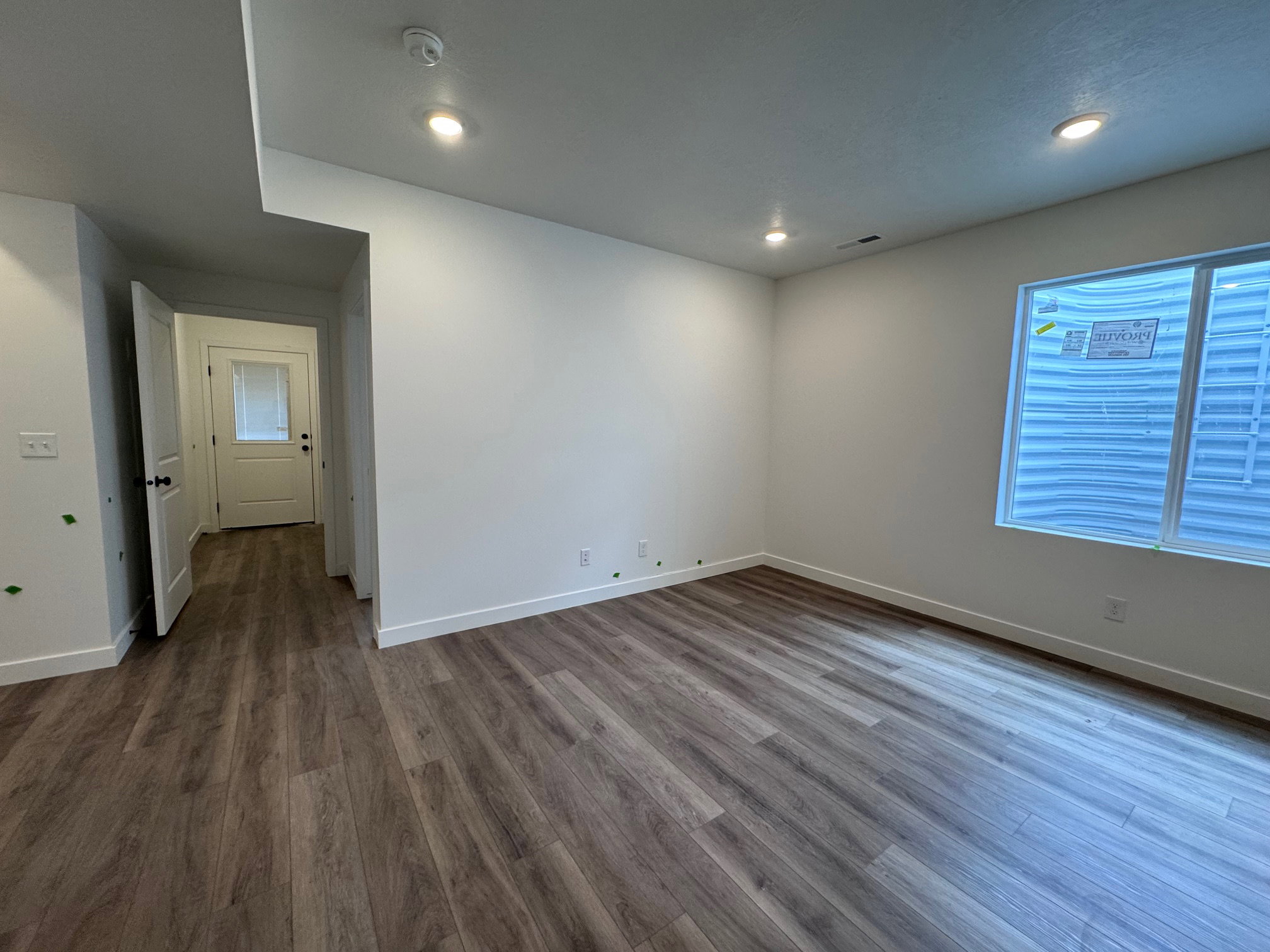 Spacious room featuring wood-finish flooring, white walls, and recessed lighting