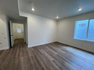 Spacious room featuring wood-finish flooring, white walls, and recessed lighting