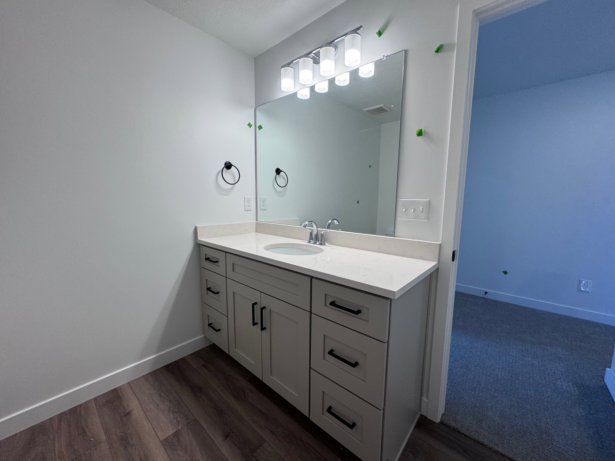 Bathroom vanity featuring a light gray cabinet with black hardware, a light-colored countertop, and an undermount sink