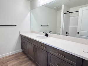 Dual sink vanity with stone-finish countertop, undermount sinks, wood-finish cabinetry, and matte black fixtures