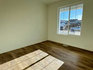 Spacious room featuring wood-finish flooring, light-toned walls, and a large window with white framing