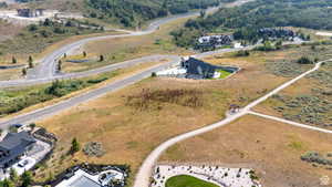 Expansive undeveloped land featuring natural terrain with scattered brush, a partially visible gravel path, and distant paved roadways