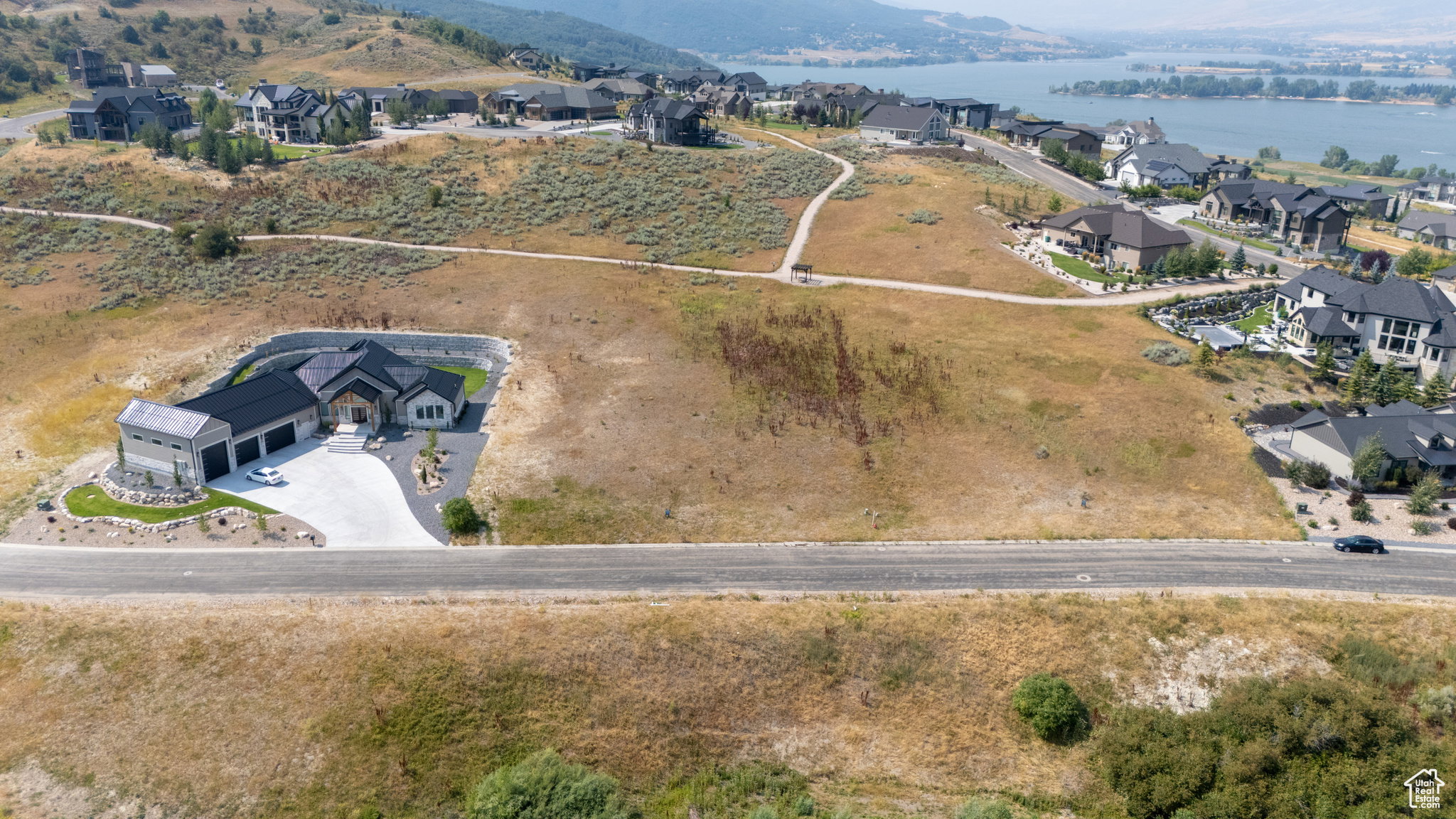 Modern hillside residence featuring a multi-car garage, expansive concrete driveway, and landscaped rock gardens