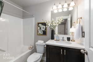 White shower-tub combination unit with a dark wood-finish vanity, white countertop, and integrated sink