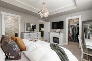 Bedroom featuring a decorative ceiling, a beaded chandelier, and an electric fireplace with a patterned tile surround