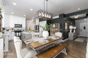 Open-concept kitchen and dining area featuring a kitchen island with seating, stainless steel appliances, white cabinetry, and wood-finish flooring