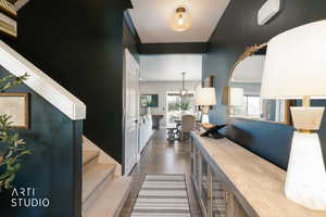 Hallway featuring dark blue walls, hardwood-finish flooring, a built-in console table, and a staircase with white balusters