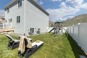 Expansive backyard featuring a manicured lawn, a white privacy fence, and a multi-level play structure