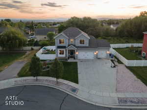 Two-story residence featuring a light gray exterior, dark shingle roof, and a three-car garage
