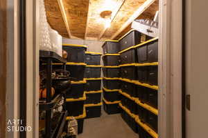 Unfinished basement storage area featuring exposed wood ceiling joists and concrete walls