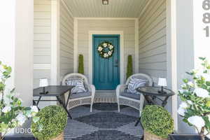 Covered front porch featuring durable siding, a vibrant teal entry door, and recessed lighting