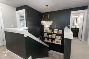 Staircase featuring a multi-tiered crystal chandelier, a dark accent wall, and built-in shelving