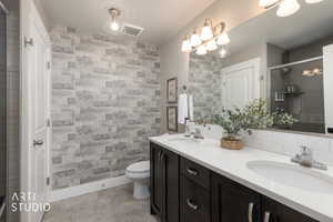 Bathroom featuring a dual vanity with dark wood-finish cabinetry, white countertops, and chrome fixtures