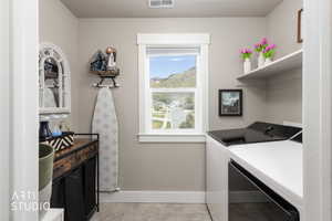 Functional laundry space featuring a window, built-in shelving, appliances, wood-finish countertop, and base cabinetry