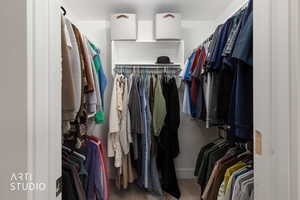 Walk-in closet featuring white built-in shelving, multiple hanging rods, and carpet flooring