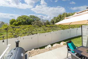 Outdoor patio featuring concrete surfacing, a white privacy fence, and string lighting