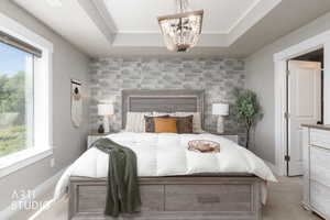 Tray ceiling with a decorative chandelier, a textured accent wall, and wood-finish flooring