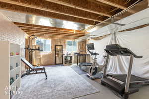 Expansive unfinished basement featuring exposed ceiling joists, ductwork, and a brick-look accent wall