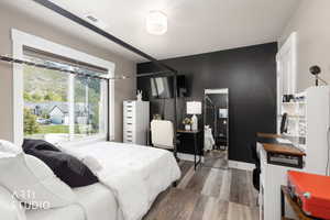 Spacious room featuring a large window, plank flooring, a dark accent wall, and a built-in shelf unit