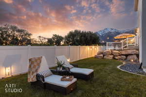 Expansive backyard featuring a manicured lawn, white vinyl fencing, and a multi-level rock retaining wall