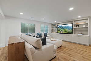Recessed lighting illuminates this bright living area featuring wood-finish flooring