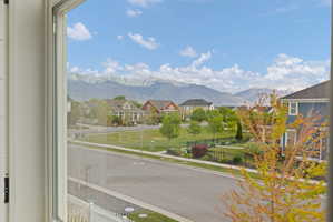 Expansive mountain range backdrop framing a neighborhood park, manicured green spaces, and a tree-lined street