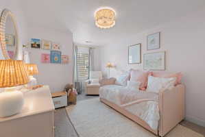 Bedroom featuring light pink walls, wood-finish flooring, a white ceiling, and a decorative flush-mount light fixture