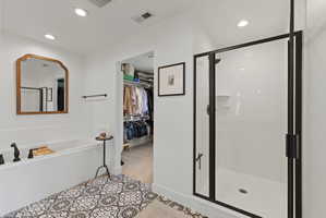 Bathroom featuring a soaking tub, glass-enclosed shower with black trim, and patterned floor tile