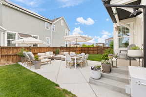 Expansive concrete patio with a built-in fire feature, offering ample space for outdoor dining and lounge areas