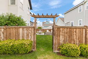 Backyard featuring a wood pergola entryway and a manicured lawn