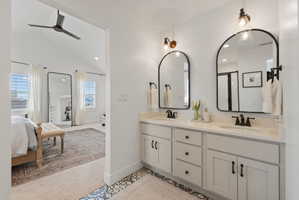 Dual vanity with white cabinetry and integrated sinks, accented by black-framed arched mirrors and wall-mounted light fixtures