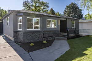 Contemporary exterior featuring dark gray stucco siding and a stone veneer foundation