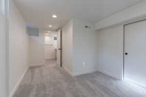 Carpeted interior space featuring recessed lighting and a window well