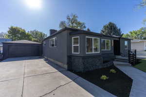 Contemporary-style residence featuring a dark gray stucco exterior with black stone accents