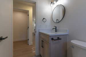 Bathroom vanity featuring wood-finish cabinetry, a white countertop, and a matte black single-handle faucet