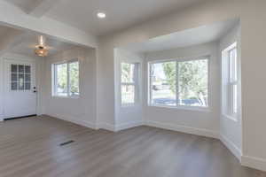 Spacious interior featuring light wood-finish flooring, white walls, and a multi-paned glass entry door