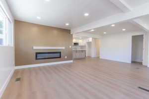 Open concept living space featuring wood-finish flooring, recessed lighting, and a linear electric fireplace with a white mantel