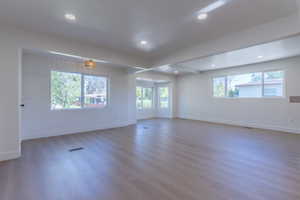 Spacious room featuring light wood-finish flooring, recessed lighting, and multiple windows