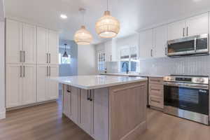 Modern kitchen featuring a central island with a light wood-finish base and a white countertop