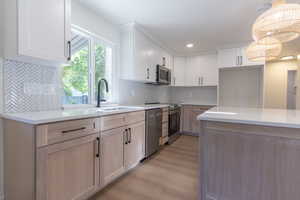 Contemporary kitchen featuring two-tone cabinetry, light-toned countertops, and stainless steel appliances