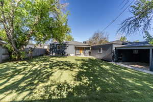 Expansive backyard featuring a manicured lawn, mature trees, and a privacy fence