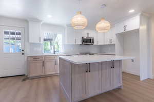 Kitchen featuring a central island with countertop seating, two-tone cabinetry, wood-finish flooring, recessed lighting, and woven pendant fixtures
