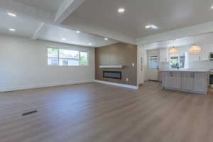Open-concept living space featuring wood-finish flooring, recessed lighting, and a linear electric fireplace