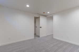 Carpeted room featuring recessed lighting, white walls, and white trim, with two doorways revealing additional interior spaces